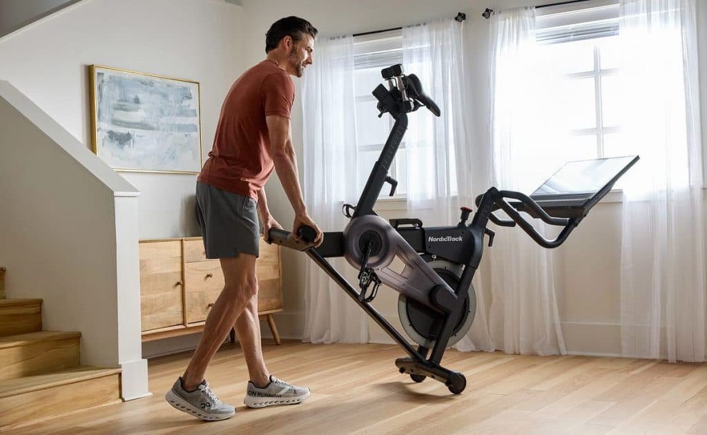 Individual moving a NordicTrack exercise bike in a home space, demonstrating portability and space-conscious design.