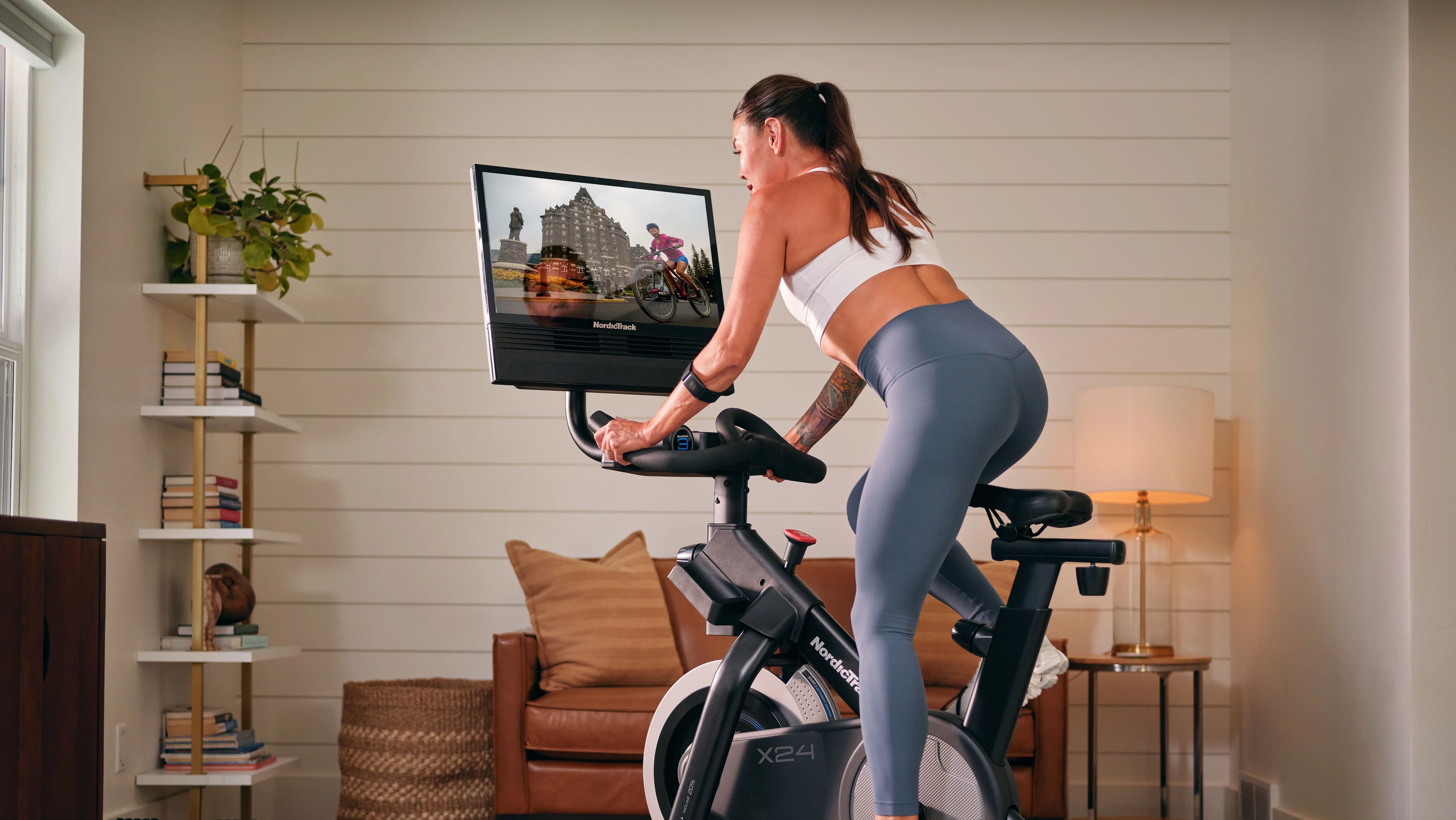 Rider on a NordicTrack X24 Bike following an iFIT guided cycling session on the built-in 24-inch HD touchscreen — at-home connected fitness for consistent cardio training