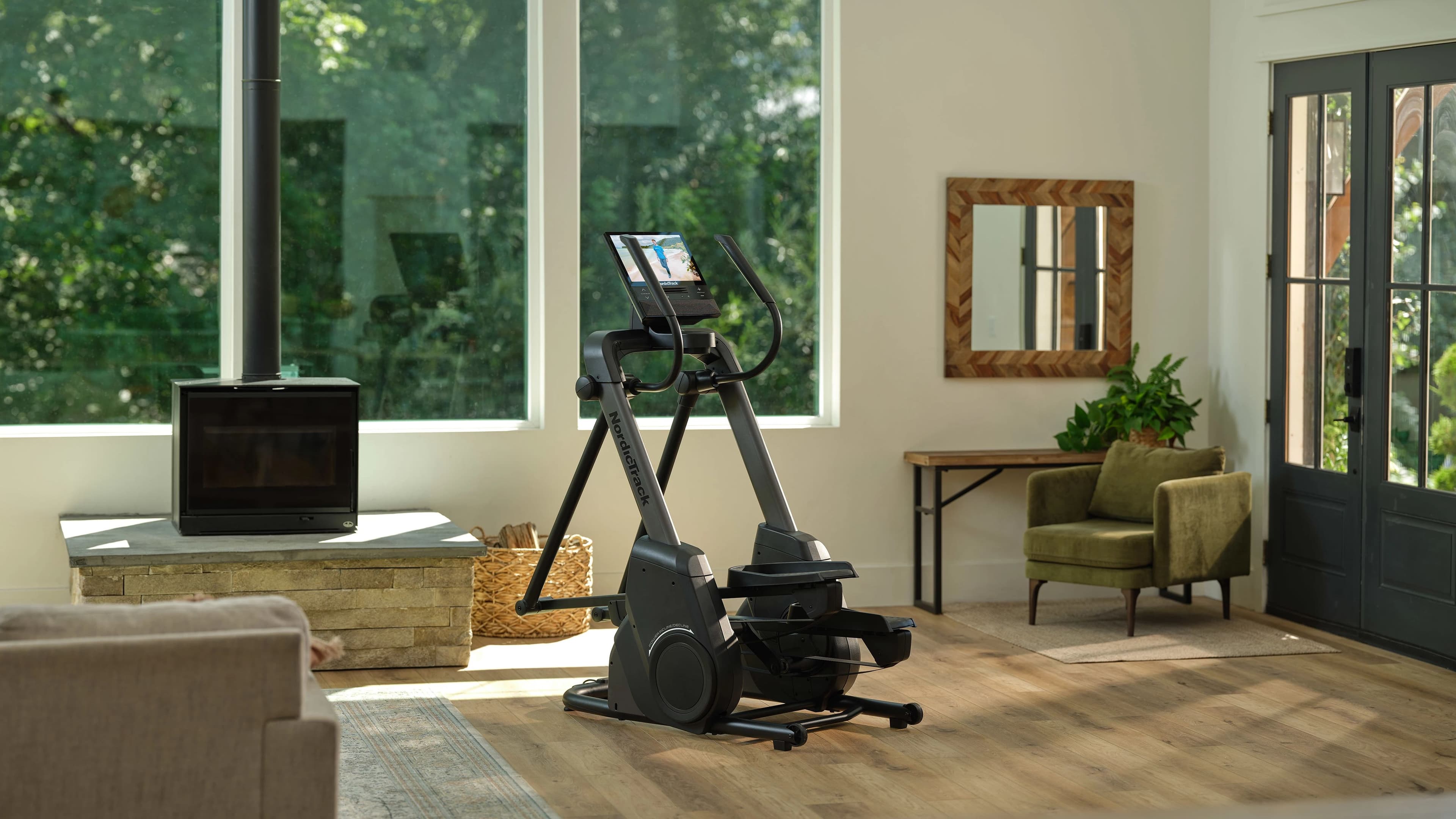 NordicTrack X16 elliptical trainer in a bright home living room with large windows and natural light, iFIT touchscreen visible