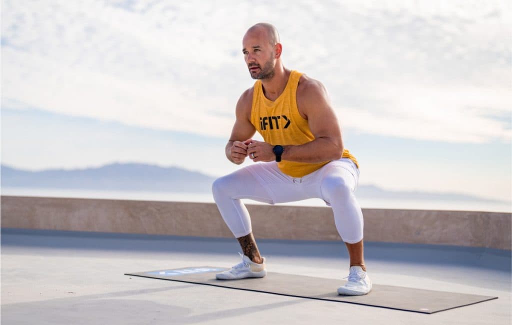 Trainer performing a controlled squat outdoors, highlighting compound movements that help preserve muscle during weight loss.