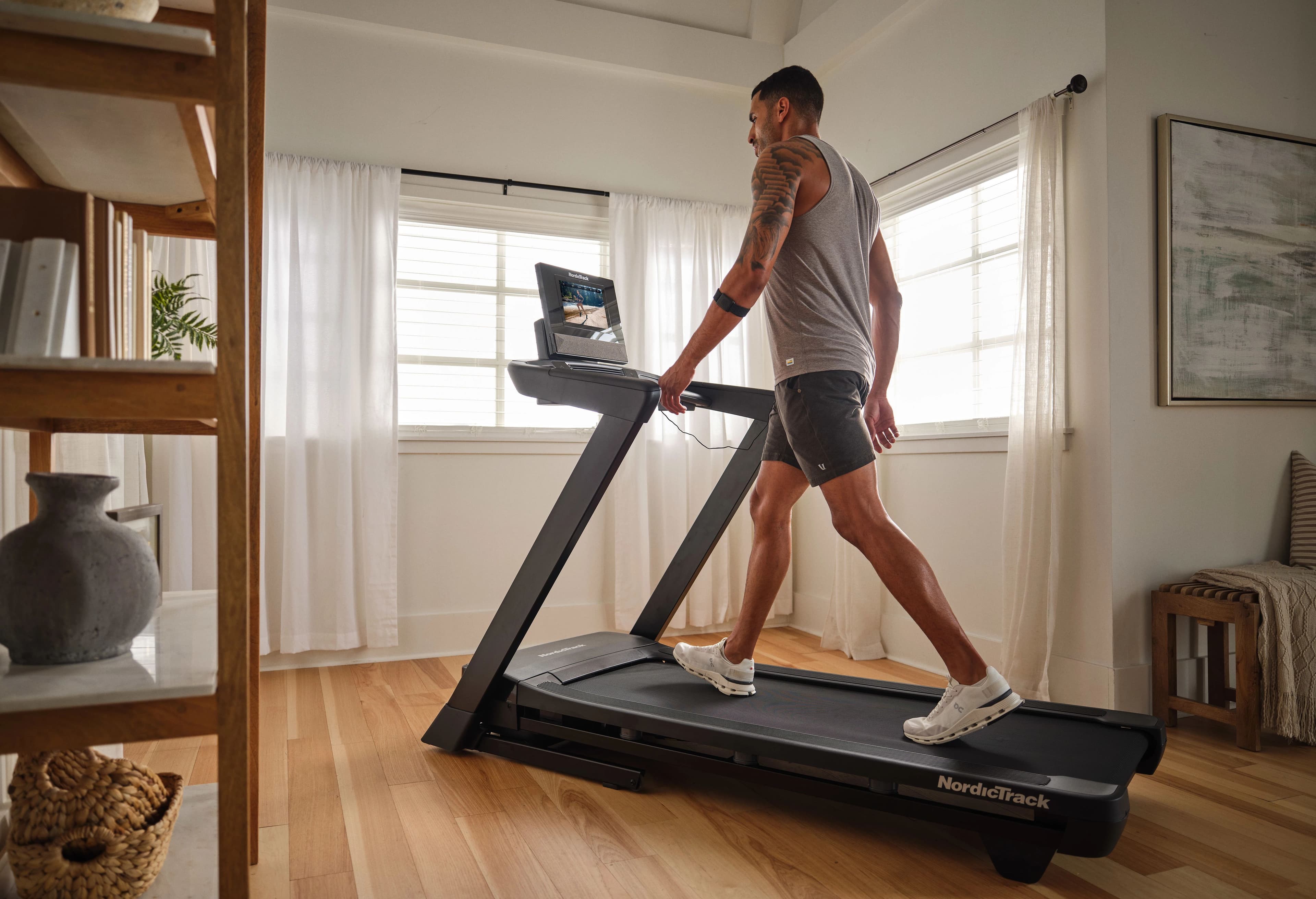 Man walking on the NordicTrack T Series 10 treadmill in a home setting — foldable treadmill with touchscreen display for walking and light jogging workouts.