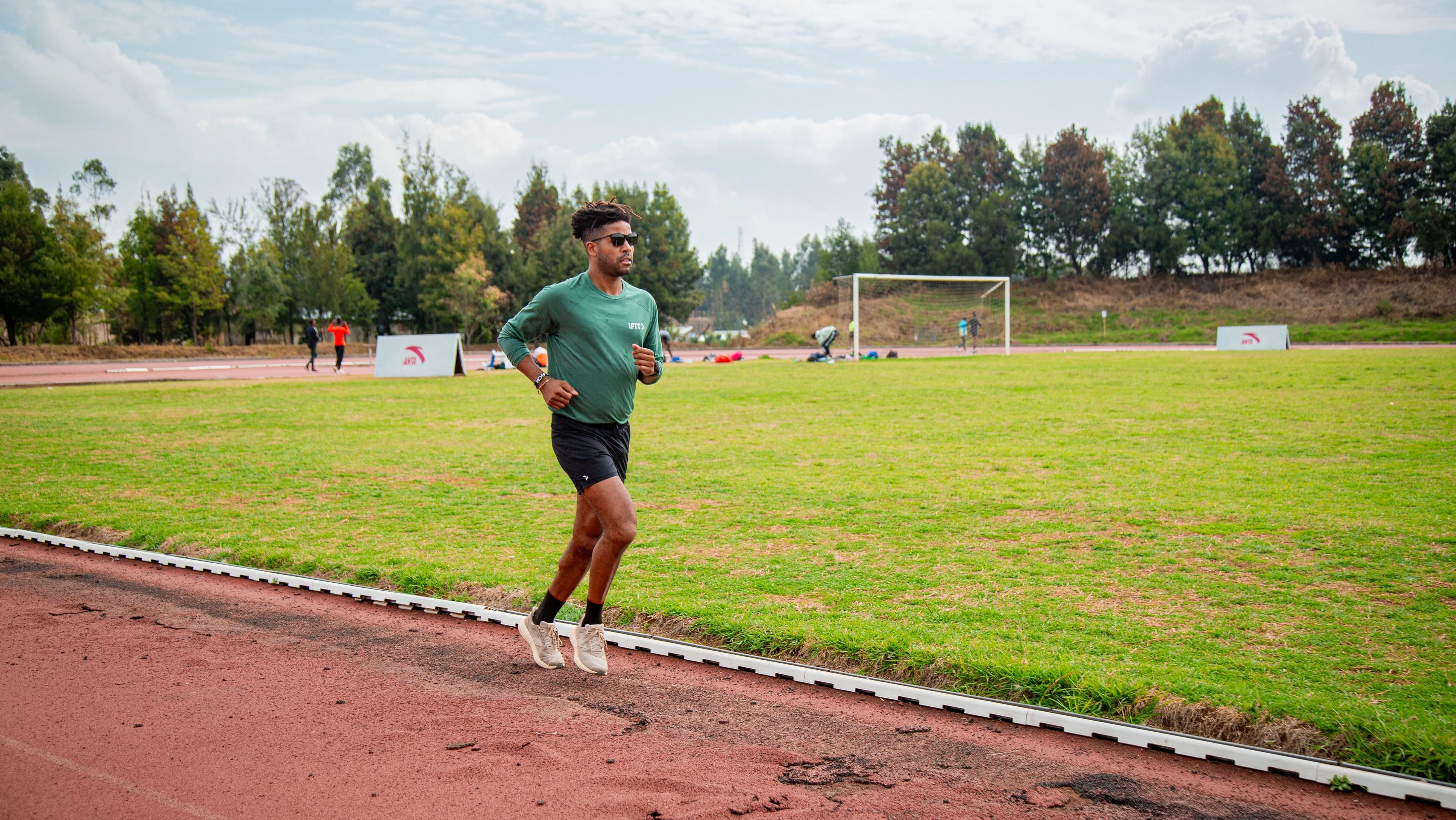 Trainer Knox Robinson running on an outdoor track during a cardio workout, demonstrating steady pace and endurance training in a natural setting