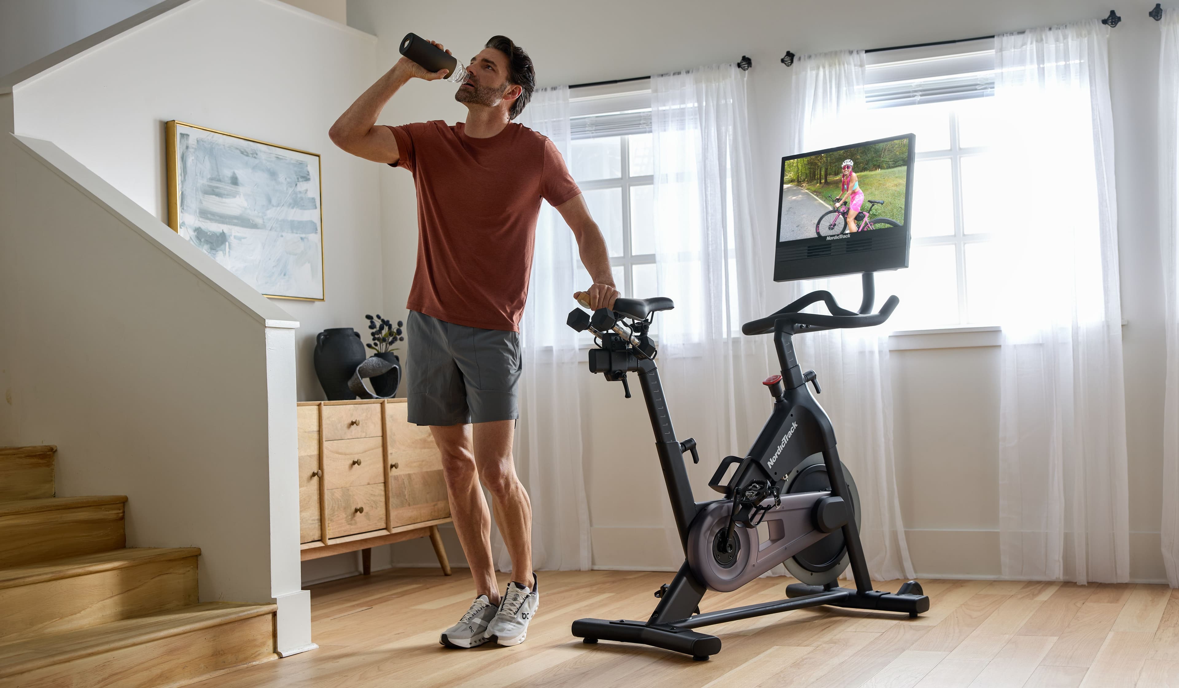 NordicTrack S24 Studio Bike shown at home with iFIT touchscreen displaying a live cycling workout. Explore connected home cycling with adaptive trainer-led programs.