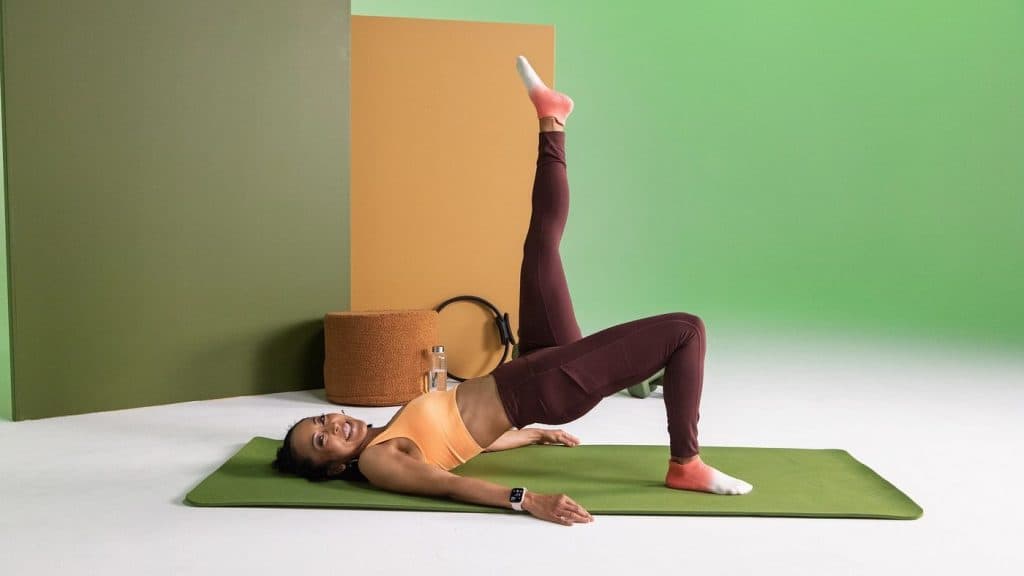 Individual performing a controlled glute bridge variation on a mat, representing low-impact strength training options during weight loss.